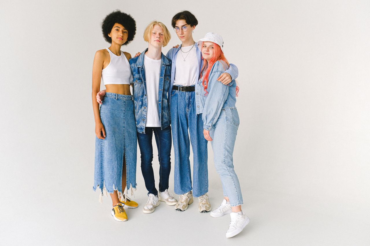 services-02 Full length of confident multiracial friends in casual clothes standing in studio while hugging on white background while looking at camera
