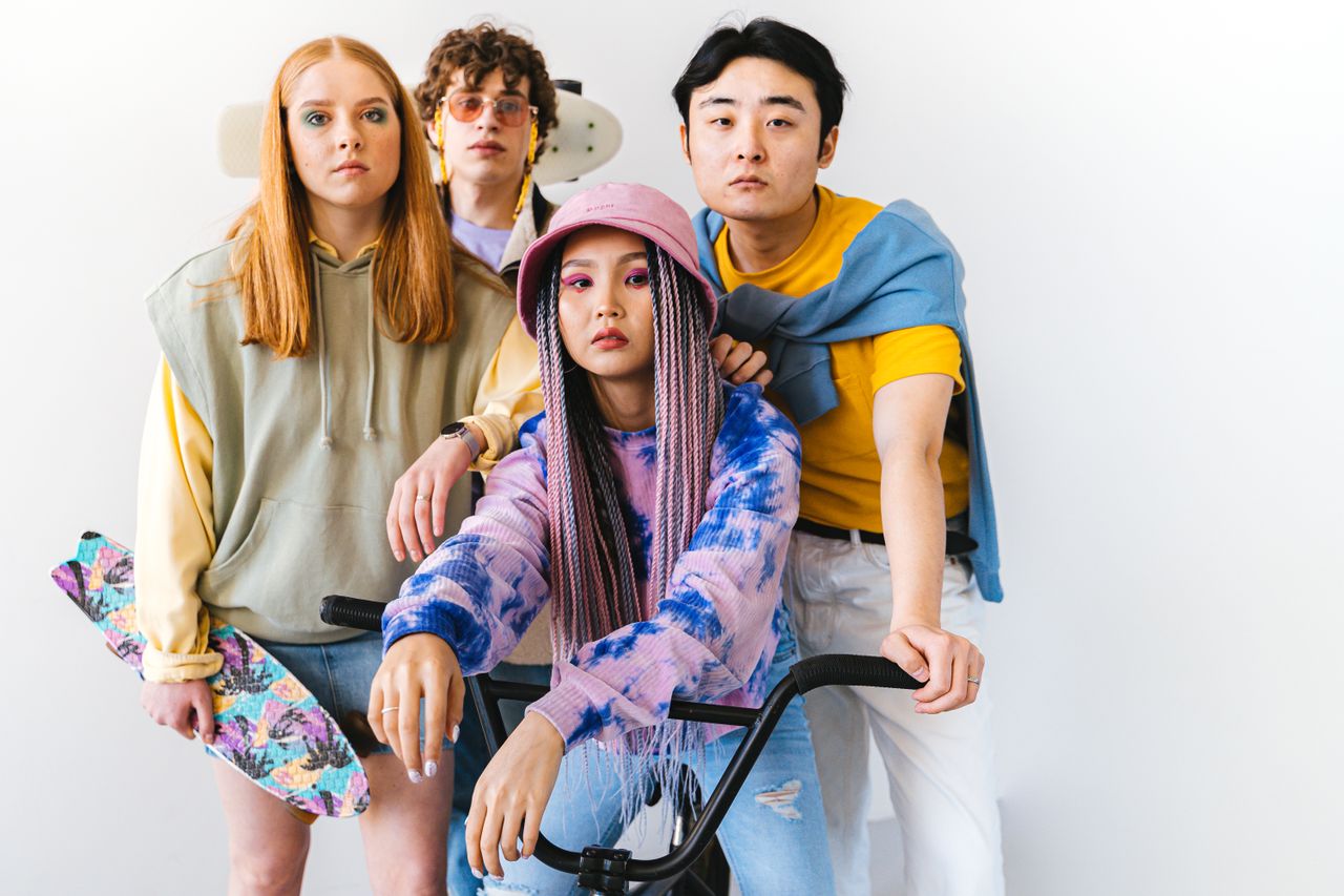 services-04 A trendy, diverse group of friends with unique fashion and hairstyles posing indoors with skateboards and a bike.