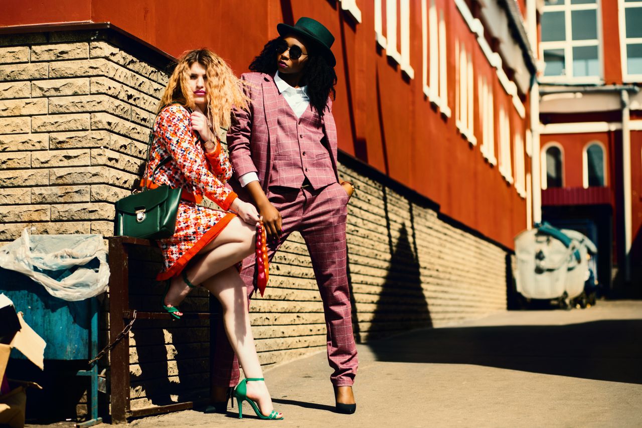 hero-img-02 Fashionable duo posing outdoors in vibrant outfits, embracing urban style and confidence.