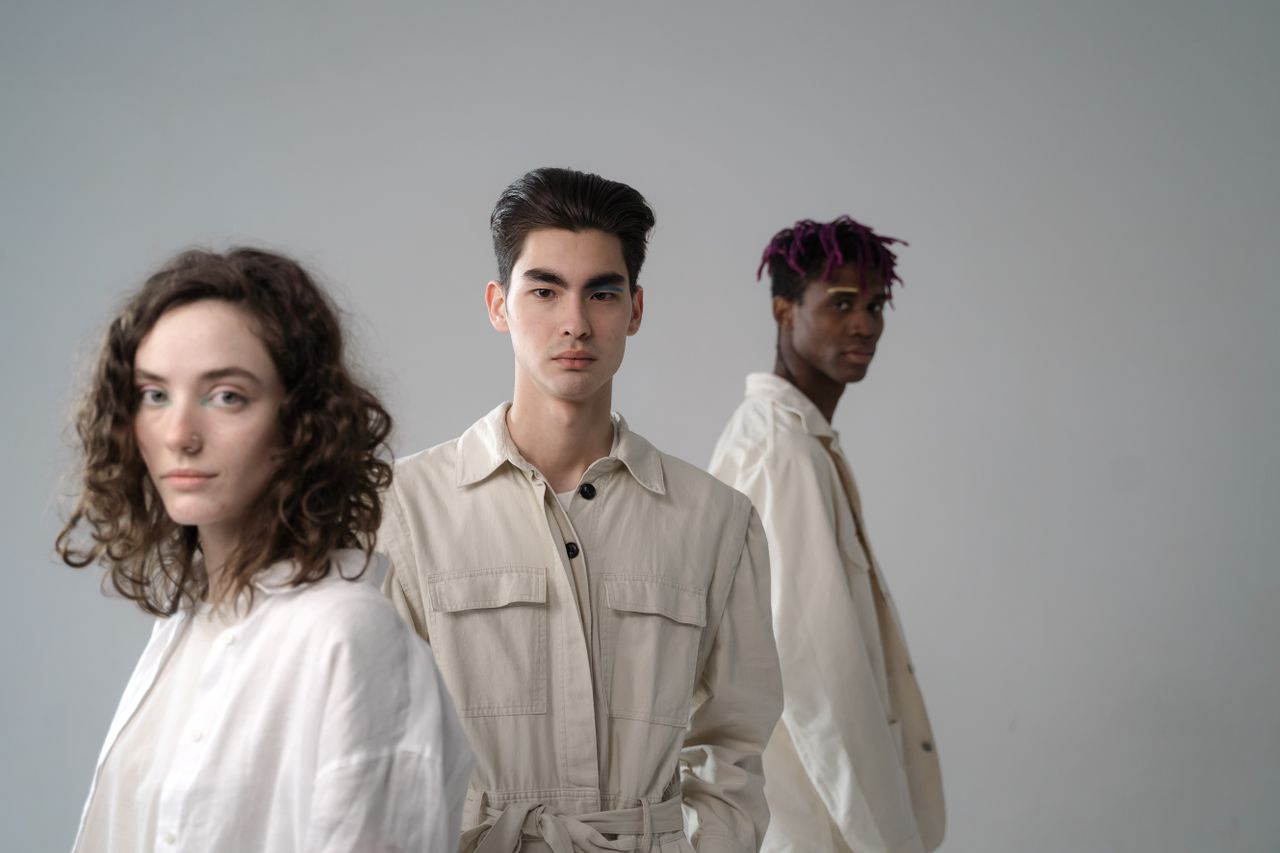 services-03 Group of diverse multiethnic young people wearing light beige and white cotton clothes standing in studio and looking at camera on gray background